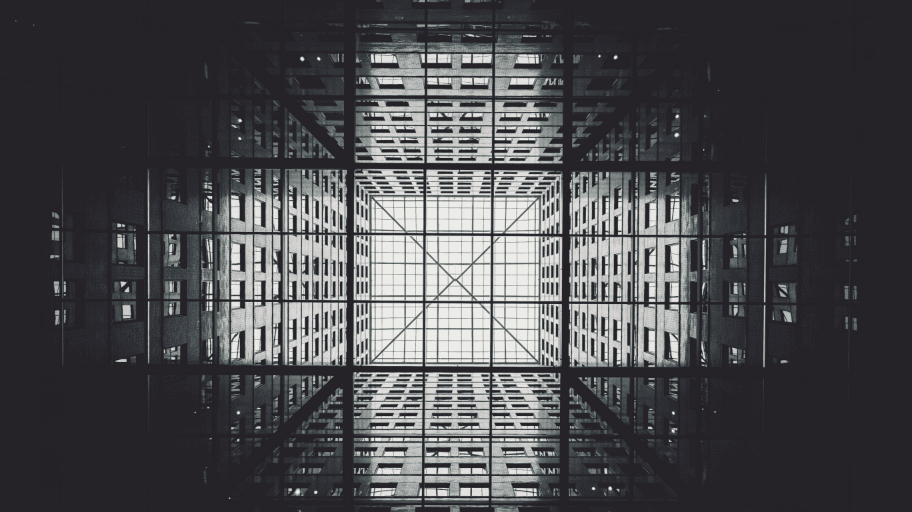 Upward view of geometric architectural structure from internal lobby of building with view of skylights.